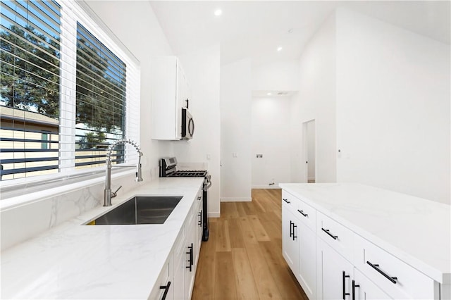 kitchen featuring white cabinetry, sink, light stone counters, and appliances with stainless steel finishes