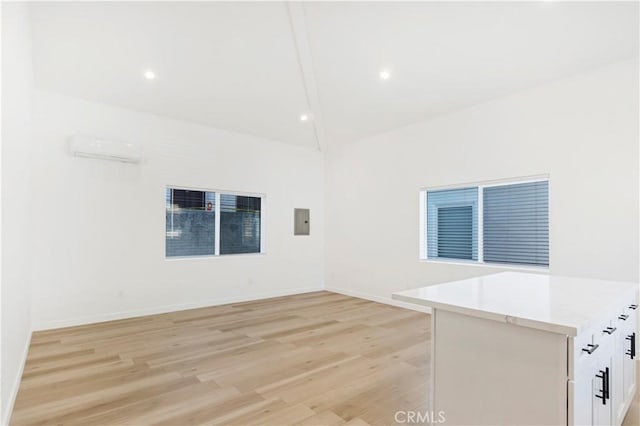 unfurnished room featuring a wall mounted air conditioner, electric panel, and light wood-type flooring