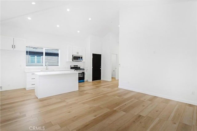 kitchen with white cabinetry, appliances with stainless steel finishes, a center island, and light hardwood / wood-style floors