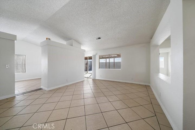 tiled spare room featuring lofted ceiling and a textured ceiling