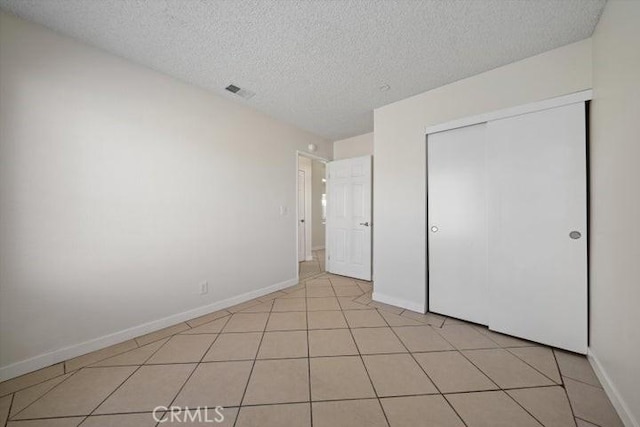 unfurnished bedroom featuring light tile patterned flooring, a closet, and a textured ceiling