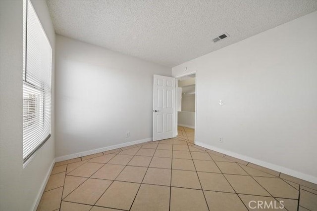 unfurnished room with light tile patterned floors and a textured ceiling