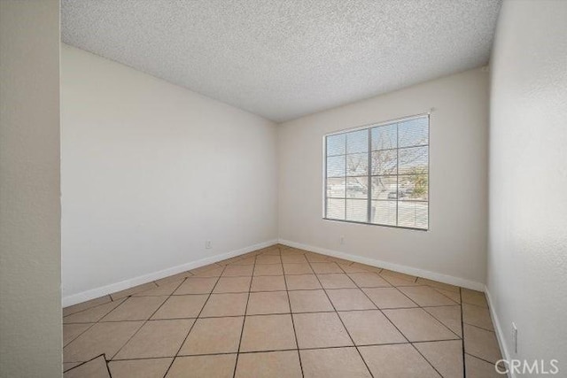 tiled empty room featuring a textured ceiling