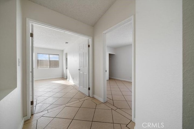 corridor featuring a textured ceiling and light tile patterned flooring