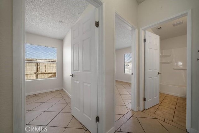 hall with light tile patterned floors and a textured ceiling