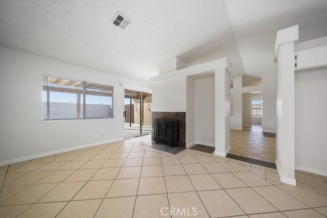 unfurnished living room featuring light tile patterned flooring, a multi sided fireplace, and a textured ceiling