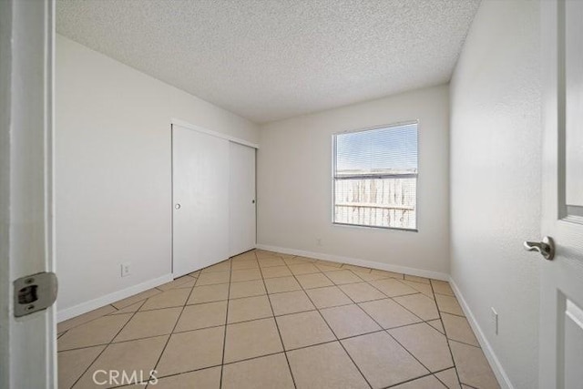 unfurnished bedroom with light tile patterned flooring, a textured ceiling, and a closet