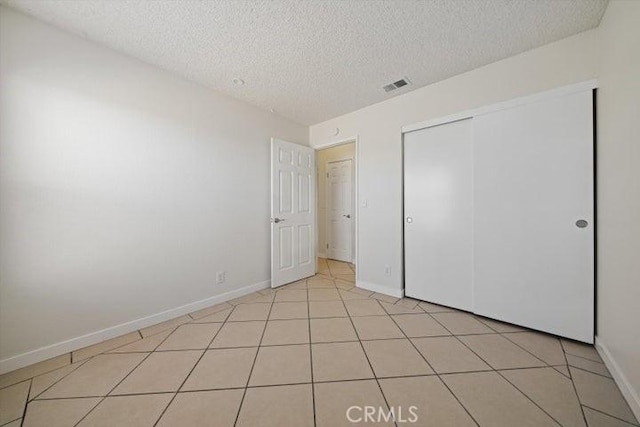 unfurnished bedroom with light tile patterned floors, a closet, and a textured ceiling