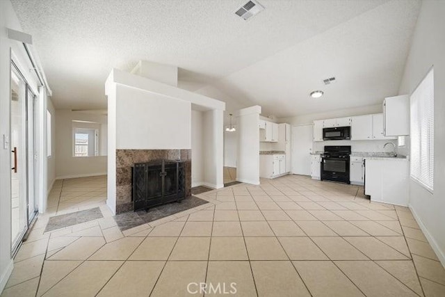 kitchen with white cabinetry, lofted ceiling, light tile patterned flooring, and black appliances