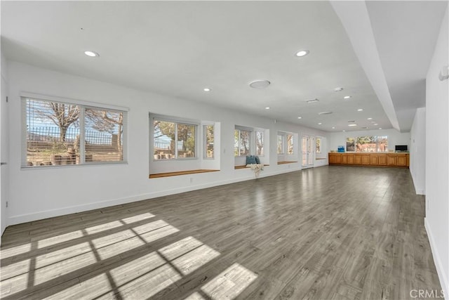 unfurnished living room with recessed lighting, light wood-type flooring, and baseboards