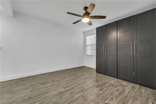 unfurnished bedroom featuring light wood-type flooring, baseboards, and ceiling fan