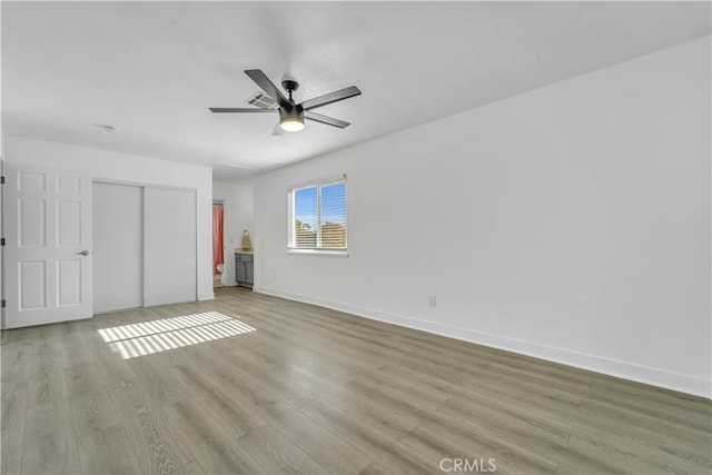 unfurnished bedroom featuring ceiling fan, wood finished floors, a closet, and baseboards