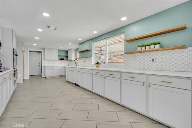 kitchen with tasteful backsplash, visible vents, light countertops, white cabinets, and open shelves