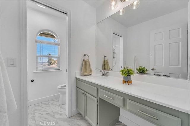 bathroom featuring baseboards, toilet, marble finish floor, and vanity