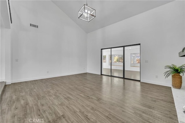 unfurnished room featuring a notable chandelier, wood finished floors, and high vaulted ceiling