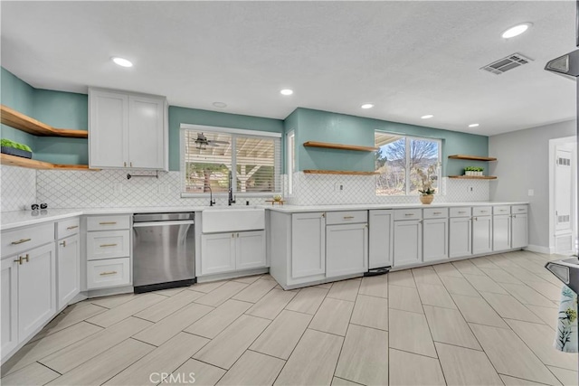 kitchen featuring open shelves, visible vents, stainless steel dishwasher, and a sink