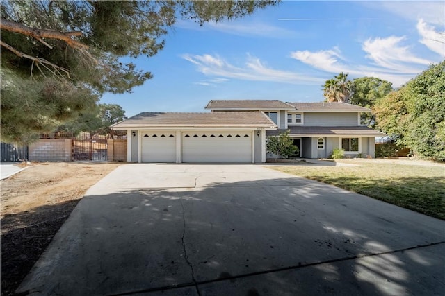 view of front of property featuring a front lawn, fence, a garage, and driveway