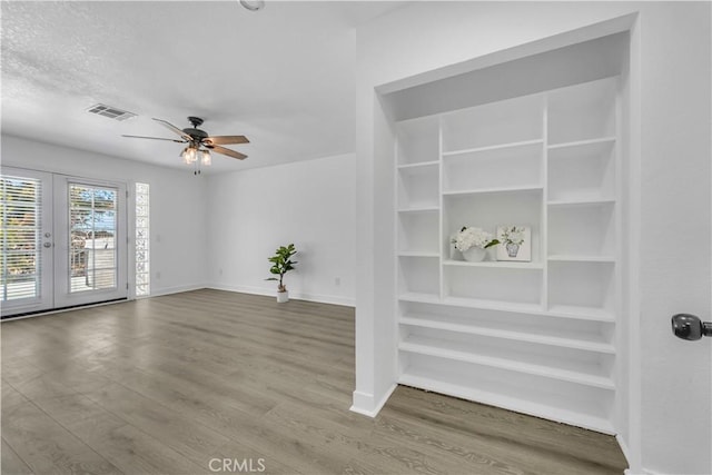 unfurnished living room with visible vents, ceiling fan, baseboards, french doors, and wood finished floors