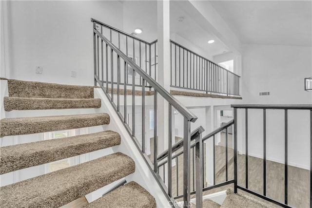 stairway with a high ceiling, recessed lighting, a healthy amount of sunlight, and visible vents