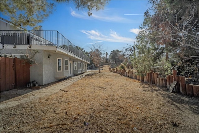 view of yard with a balcony and fence