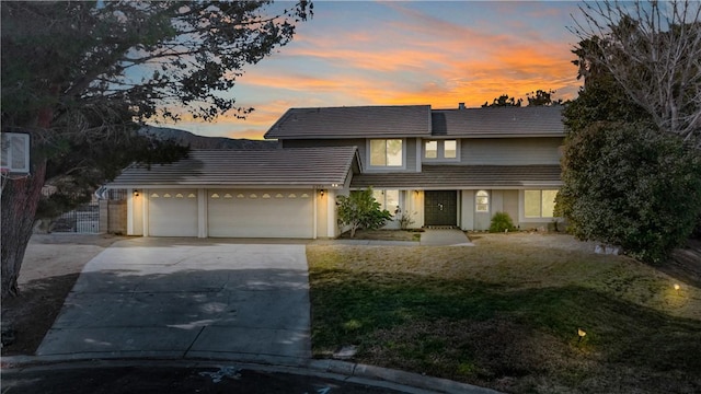 view of front of property featuring a garage, a yard, driveway, and a tile roof