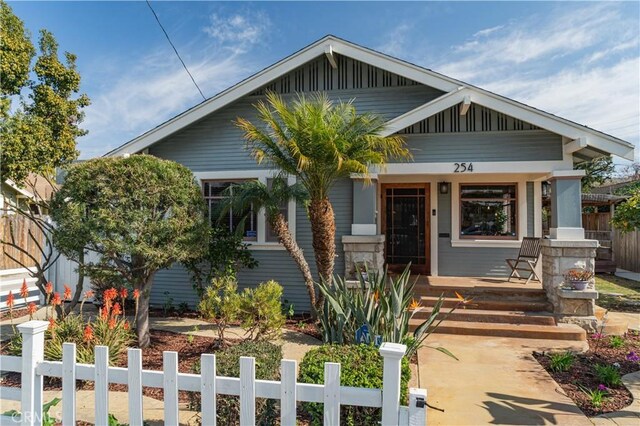 view of front facade featuring board and batten siding, a porch, and a fenced front yard