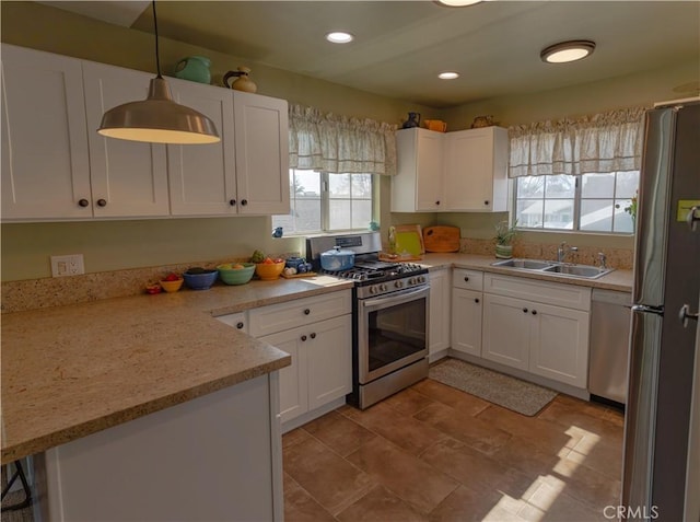 kitchen with appliances with stainless steel finishes, hanging light fixtures, and white cabinets