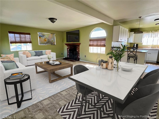 interior space with beamed ceiling, plenty of natural light, baseboards, and a brick fireplace