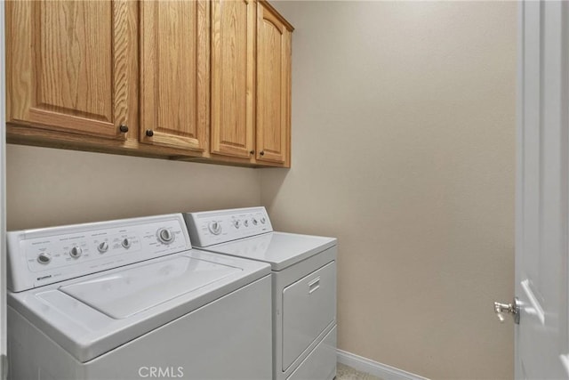 clothes washing area with cabinets and separate washer and dryer