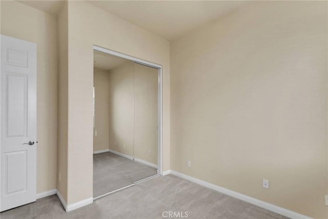 unfurnished bedroom featuring light colored carpet and a closet