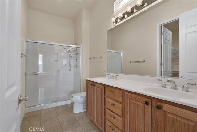 bathroom with tile patterned floors, vanity, toilet, and a shower with shower door