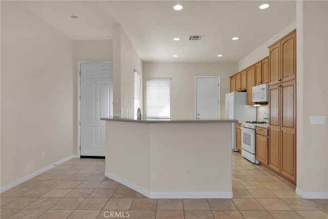 kitchen with light tile patterned flooring, white appliances, and a center island