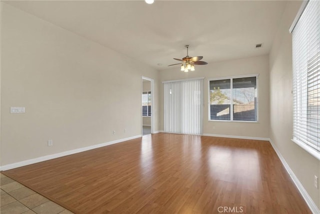 spare room featuring ceiling fan, light hardwood / wood-style flooring, and a wealth of natural light