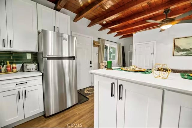 kitchen with stainless steel fridge, white cabinets, decorative backsplash, wooden ceiling, and beamed ceiling