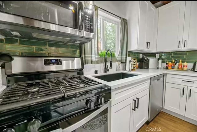 kitchen featuring sink, white cabinetry, light hardwood / wood-style flooring, appliances with stainless steel finishes, and backsplash