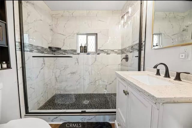 bathroom featuring vanity, a shower with door, and toilet