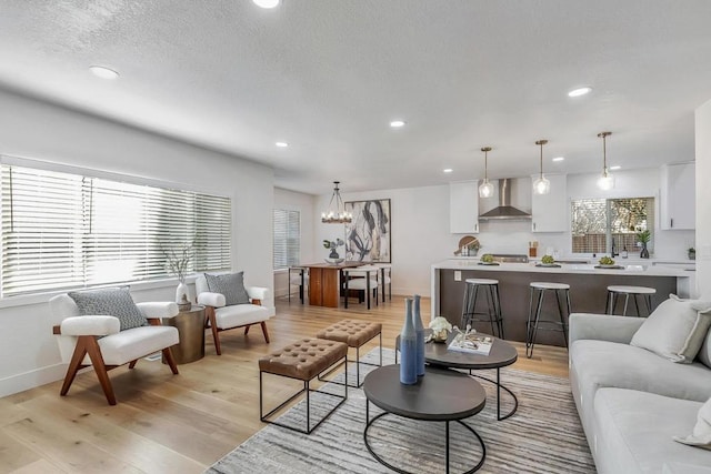 living room featuring a healthy amount of sunlight, a chandelier, and light hardwood / wood-style flooring