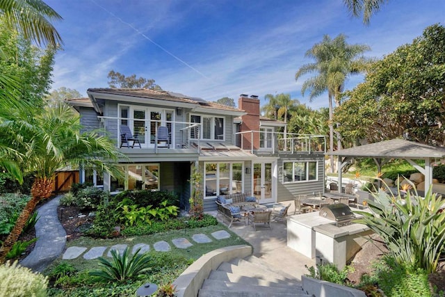 rear view of property featuring a patio, a balcony, and exterior kitchen