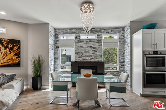 dining space with a notable chandelier, a fireplace, and light hardwood / wood-style flooring