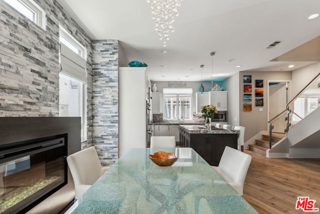 dining room with a notable chandelier, hardwood / wood-style flooring, a fireplace, and plenty of natural light