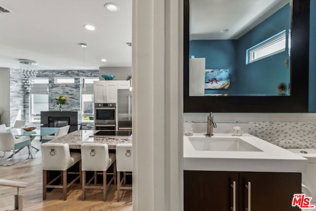 bathroom with sink, hardwood / wood-style floors, and a large fireplace