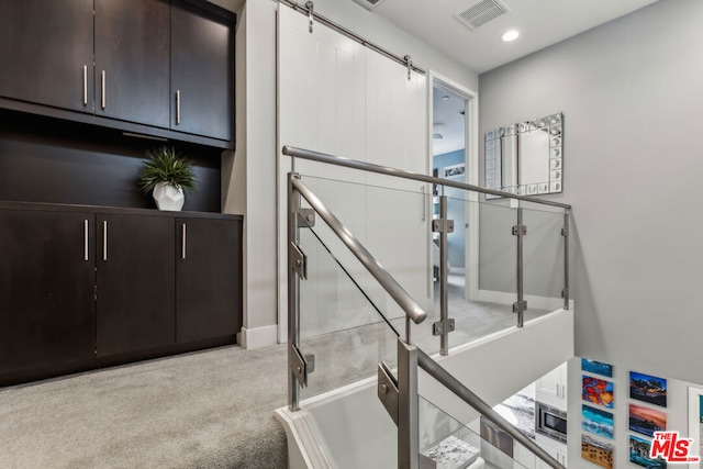 stairway featuring a barn door and carpet floors