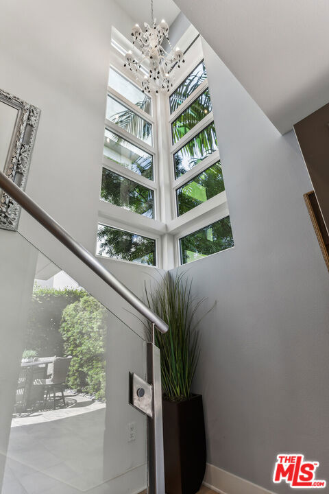 staircase with a notable chandelier, a healthy amount of sunlight, and a high ceiling