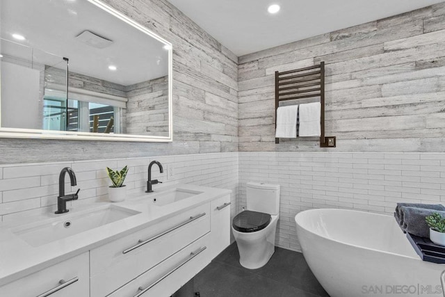 bathroom with tile patterned flooring, tile walls, vanity, a tub, and toilet