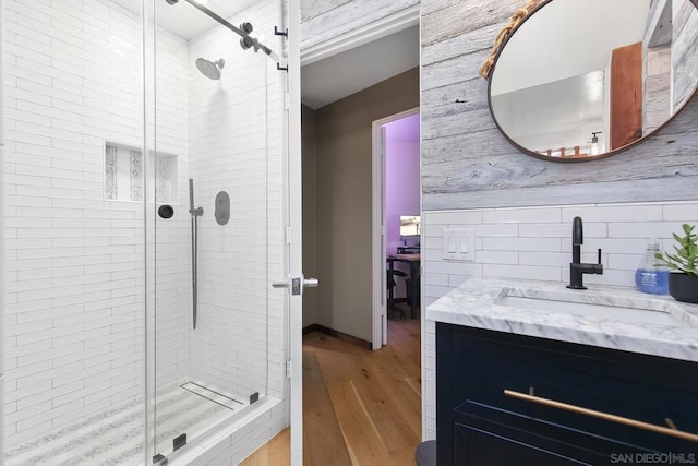 bathroom with vanity, hardwood / wood-style floors, backsplash, and a shower with shower door