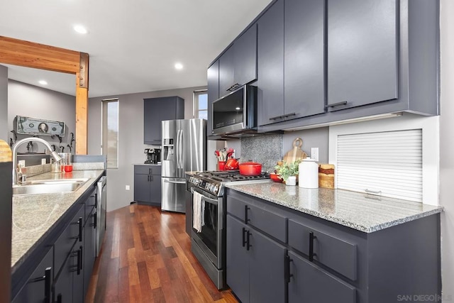 kitchen featuring appliances with stainless steel finishes, tasteful backsplash, sink, dark hardwood / wood-style flooring, and light stone counters