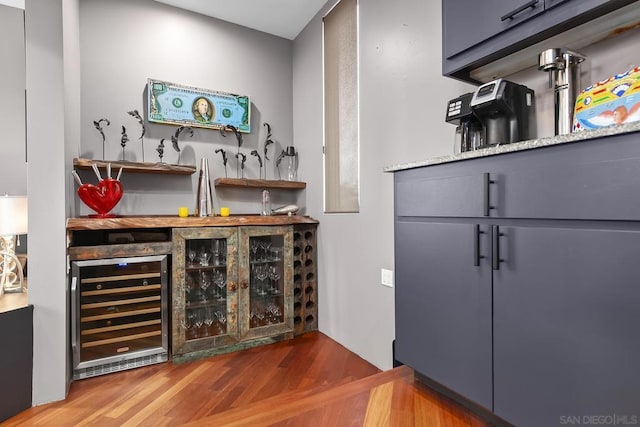 bar with hardwood / wood-style flooring and beverage cooler