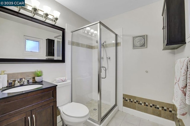 bathroom featuring vanity, toilet, tile patterned flooring, and a shower with door