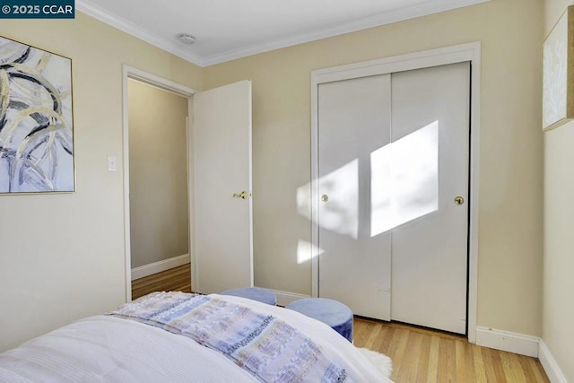 bedroom featuring crown molding, light hardwood / wood-style flooring, and a closet