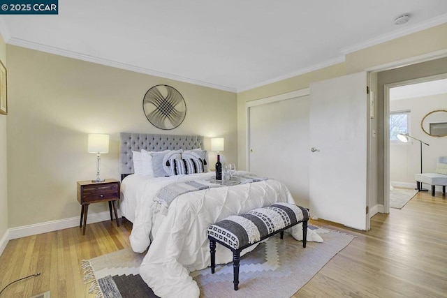 bedroom with light hardwood / wood-style flooring, ornamental molding, and a closet